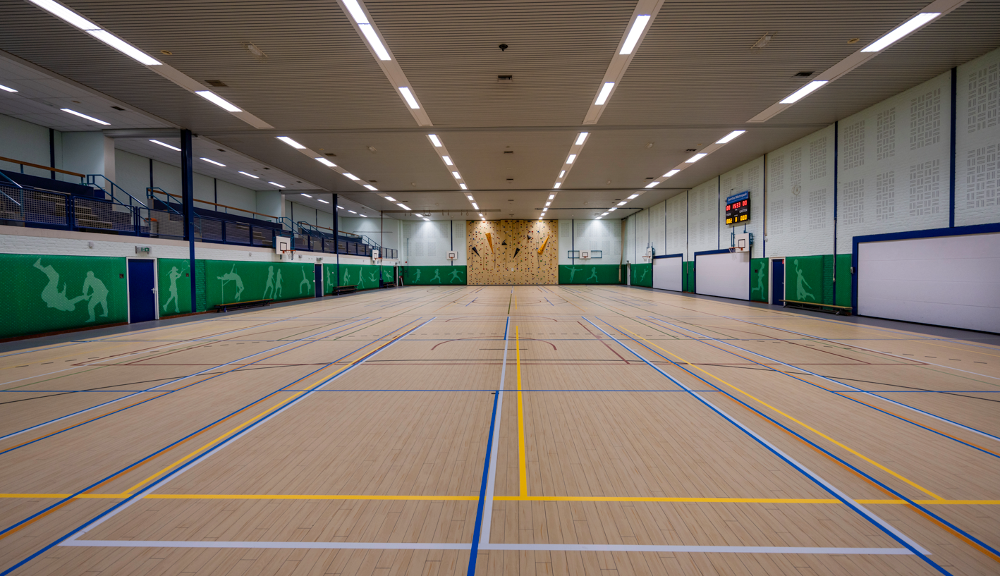 De sporthal is akoestisch verbeterd met geluiddempende wandpanelen en plafonds
